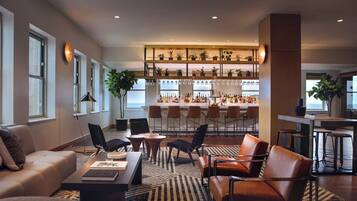 Una sala de estar moderna con zona de bar, que incluye un sofá, sillas, una mesa de centro y un bar repleto de botellas.