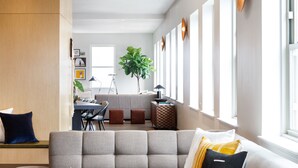 A modern living room with a sectional sofa, a coffee table, and a dining area in the background.