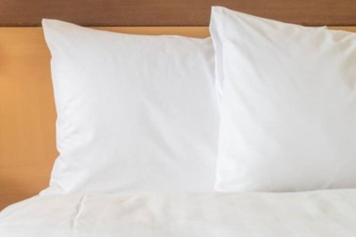 Ein Bett mit weißer Bettwäsche und einem Holzkopfteil.