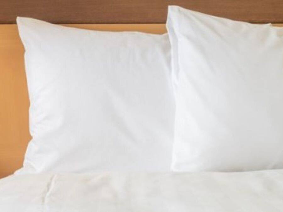 Una cama con ropa de cama blanca y cabecero de madera.