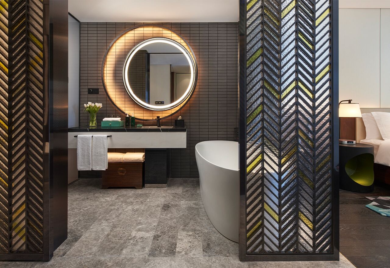 Un baño moderno con un espejo grande, una bañera independiente y un tocador con lavamanos.