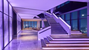 Een modern interieur met een trap naar een balkon met uitzicht op een stadsgezicht.