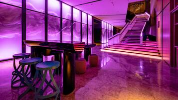 Een modern interieur met een bar, zitplaatsen en een trap naar een hoger niveau.