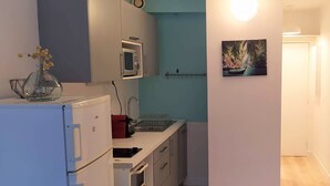 A compact kitchen with a microwave, sink, and cabinets. A painting of a boat is on the wall. - Studio - quiet seaside location with private parking (La Ciotat)