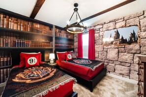 Une chambre avec deux lits, une grande bibliothèque et un mur en pierre orné d’une fresque représentant un château.