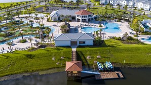 An aerial view of a resort with multiple swimming pools, a beach area, and a dock with kayaks. - Spacious 8BD/6BA Pool Home 20048 (Kissimmee)