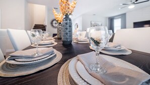 A dining table set with plates, glasses, and placemats. - Spacious 8BD/6BA Pool Home 20048 (Kissimmee)