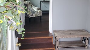 Un passage donnant sur un escalier, avec un banc en bois et un objet décoratif fixé au mur.