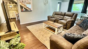 Un salon avec un canapé marron, une table basse en bois et une grande plante en pot.