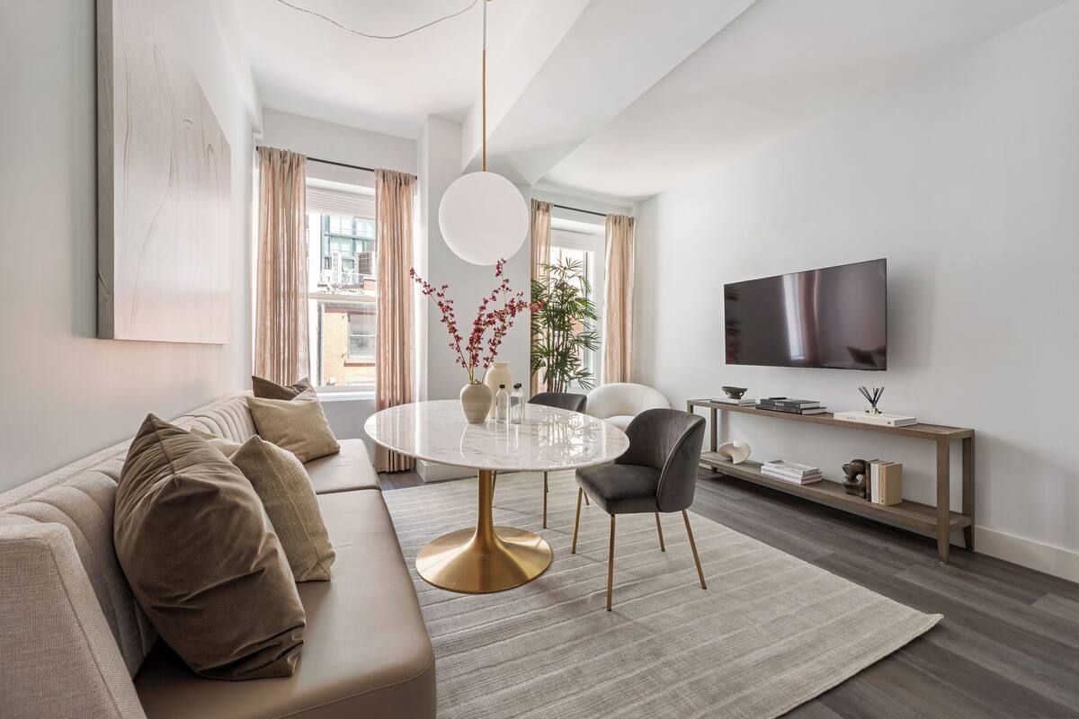 A modern living room with a round dining table, a sofa, a TV, and a bookshelf.