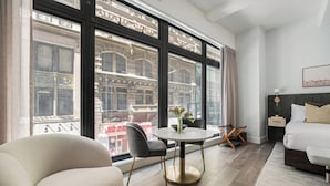 A modern hotel room with a large window, a round dining table, a sofa, and a bed. - 17John  (New York)