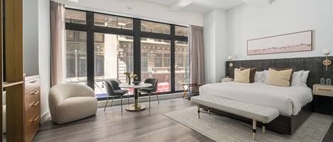 A modern hotel room with a large window, a bed, a desk, and a chair.