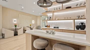 Una cocina moderna con encimera de mármol, iluminación colgante y una zona de bar con taburetes.