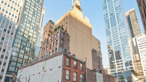 A rooftop patio with outdoor furniture, potted plants, and a view of surrounding high-rise buildings. - 17John  (New York)