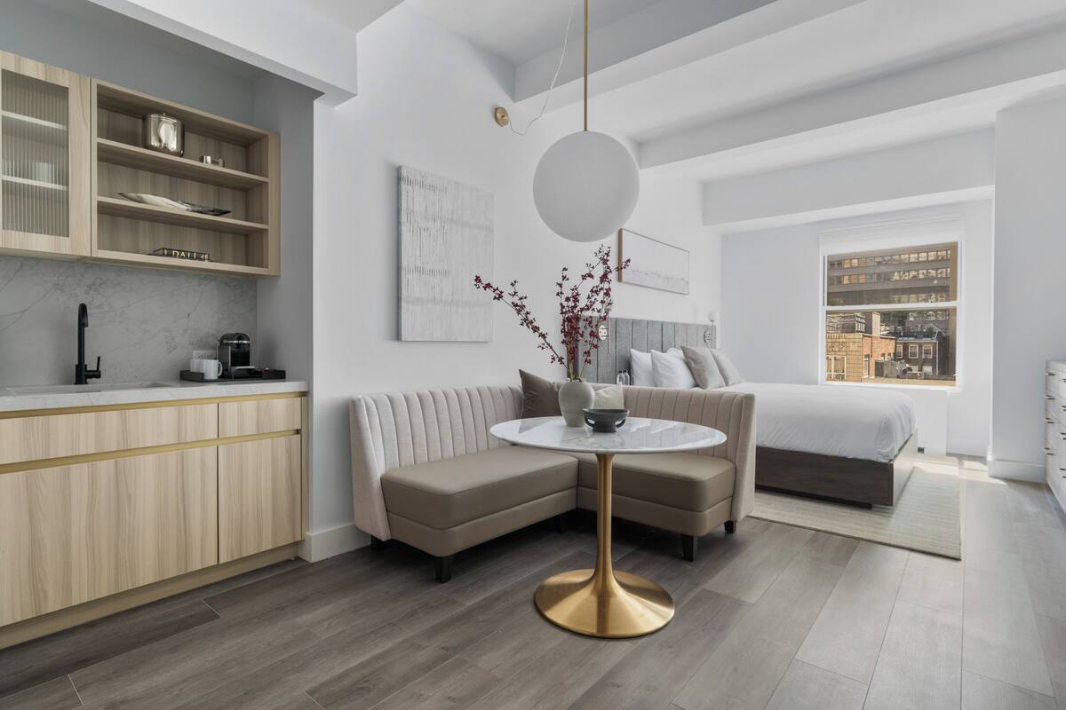 A modern interior with a kitchen, a sofa, a round table, and a bed.
