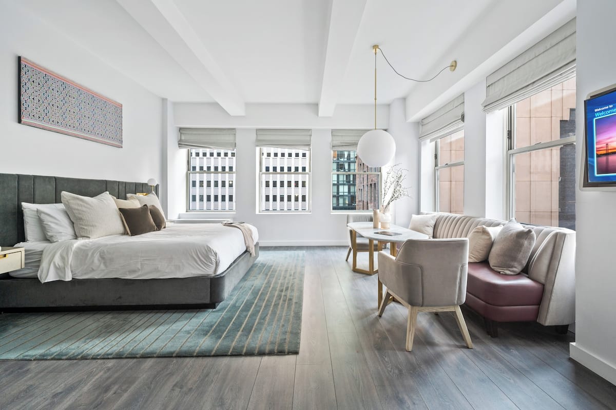 A modern bedroom with a large bed, a desk, and a sofa.