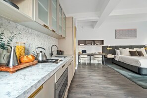 A modern kitchen with marble countertops, a wooden serving board, and a dining area with a table and chairs.