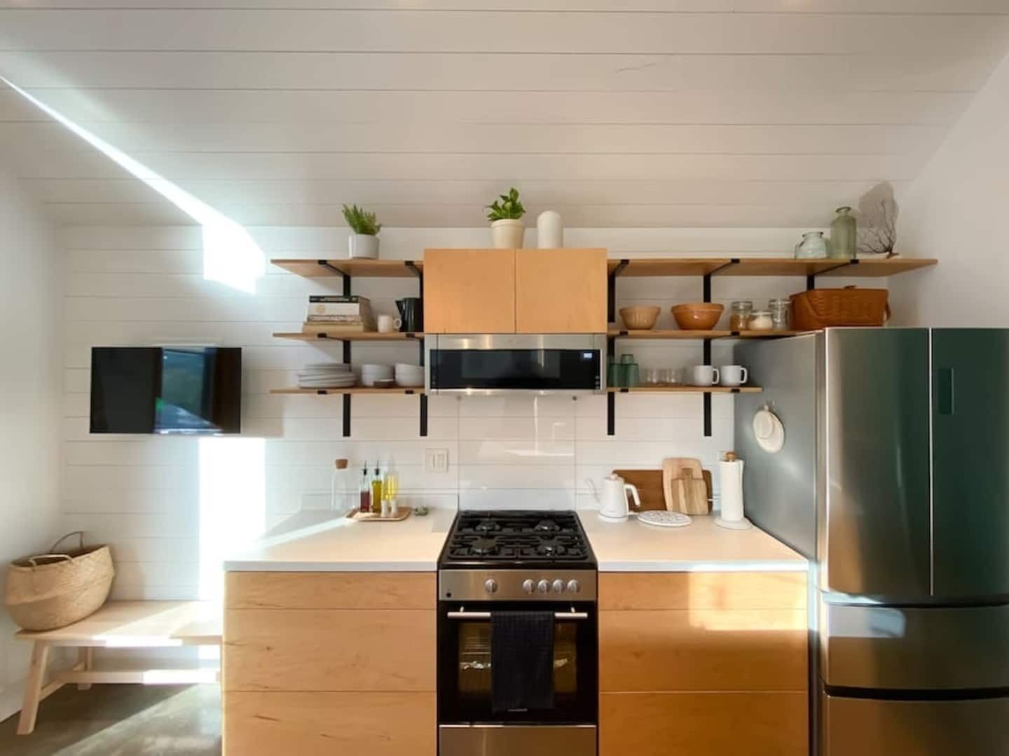 A modern kitchen with wooden cabinets, a stainless steel refrigerator, and a built-in oven.