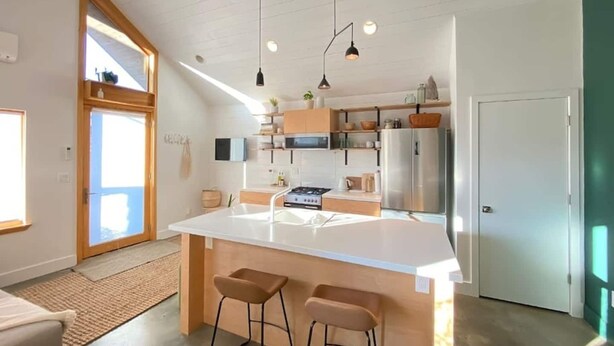 A modern kitchen with a central island, pendant lighting, and a large window. - Walkable Modern Retreat (Portland)
