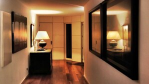 A hallway with wooden flooring, a small table with a lamp, and a framed picture on the wall.