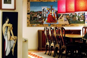 Un'area pranzo con tavolo e sedie, un quadro di grandi dimensioni appeso al muro e un termosifone.