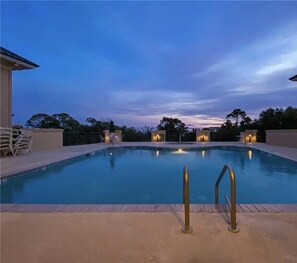 An outdoor swimming pool with a view of the sky at dusk.