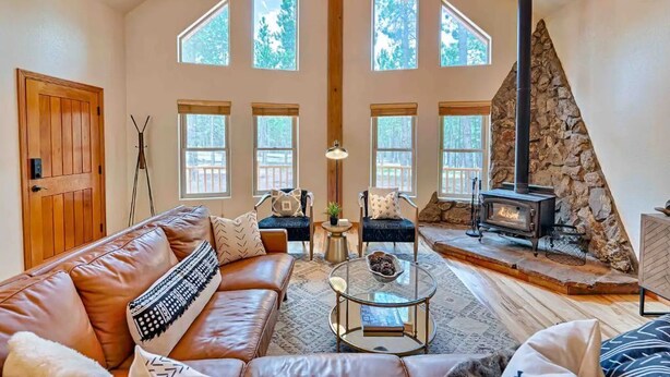 A spacious living room with a leather sofa, a coffee table, and a stone fireplace. - Lincoln Log Cabin, Tranquility close to Downtown (Flagstaff)