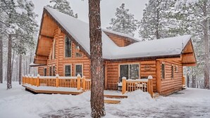 A log cabin with a wooden deck and multiple windows, surrounded by snow-covered trees. - Lincoln Log Cabin, Tranquility close to Downtown (Flagstaff)