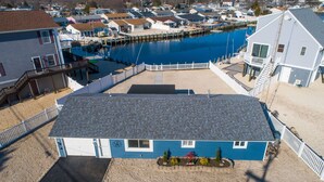 A two-story house with a blue exterior and a grey roof, located near a waterfront with docks and boats.