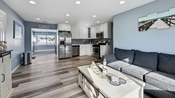 A modern kitchen with white cabinets, stainless steel appliances, and a view to the outdoors.