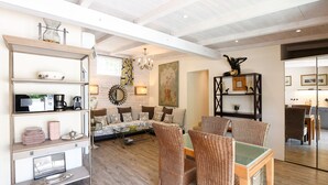 A dining area with wicker chairs, a glass-top table, and a buffet counter with shelves. - Maison - Maison Le Pacha (Calvi)