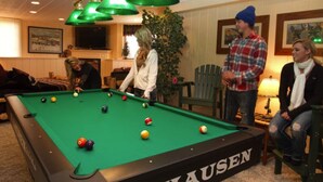 A pool table with balls, a green tablecloth, and a sign that reads "HAUSEN". - Rustic Luxury in the Northwoods l (Ironwood)
