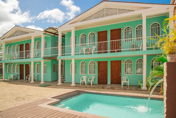 Un edificio de dos pisos con una piscina delantera.