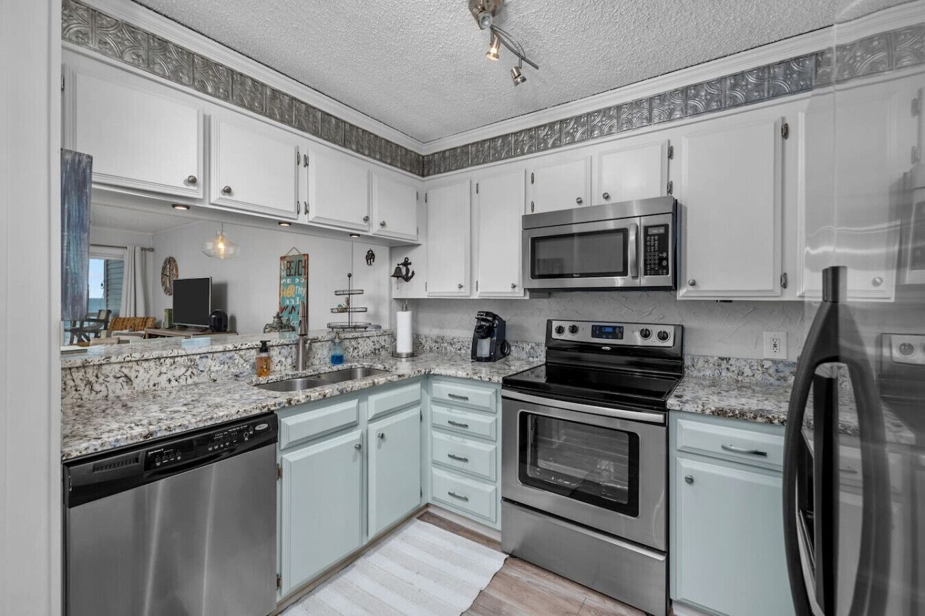 Een moderne keuken met witte kasten, roestvrijstalen apparatuur, een granieten aanrechtblad en uitzicht op de omgeving.