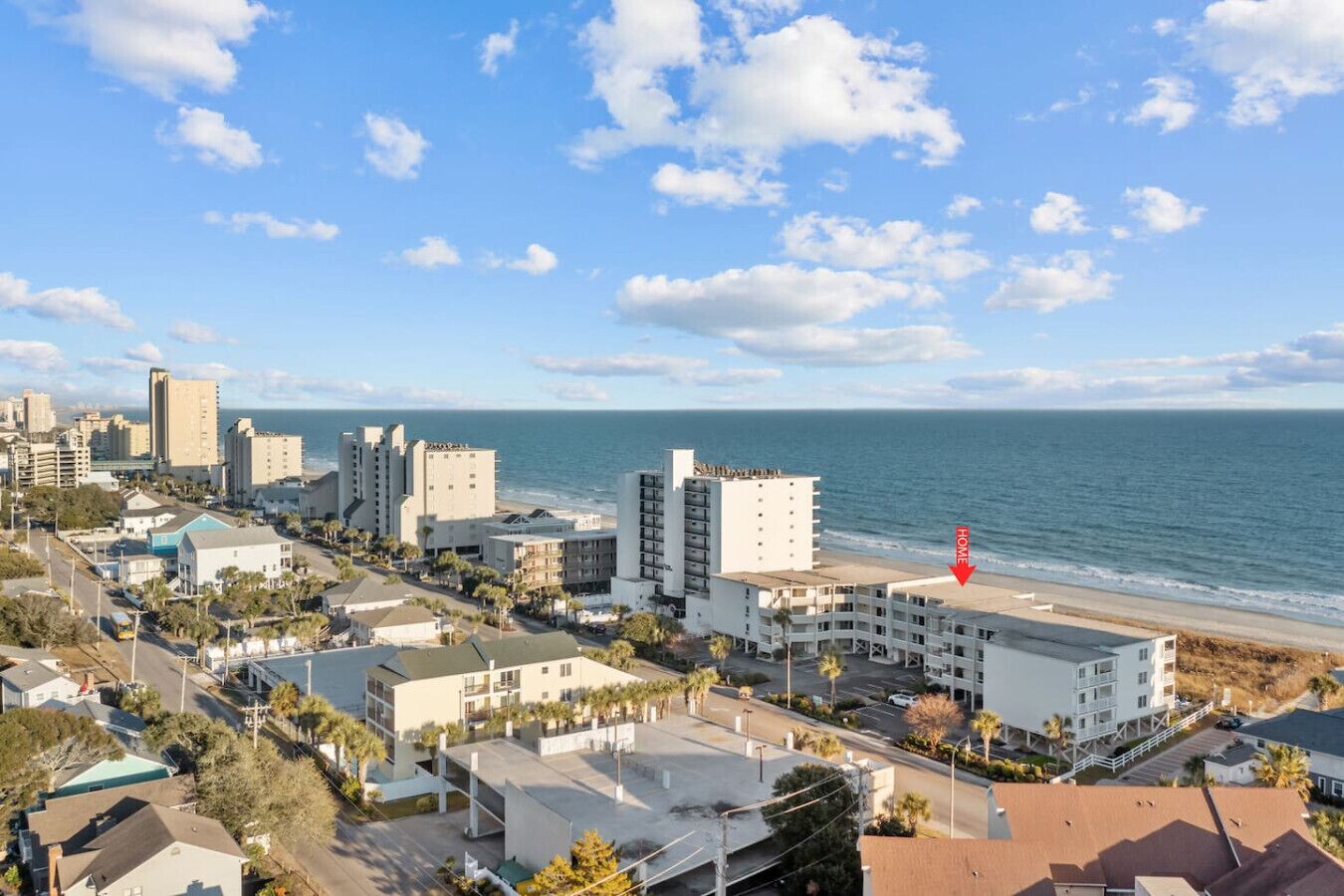 A coastal cityscape with a beachfront hotel marked by a red arrow.
