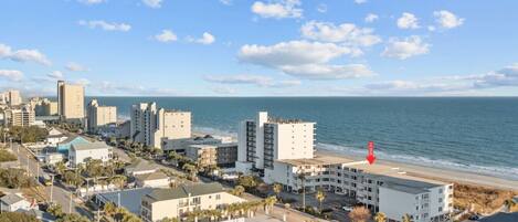 A coastal cityscape with a beachfront hotel marked by a red arrow.
