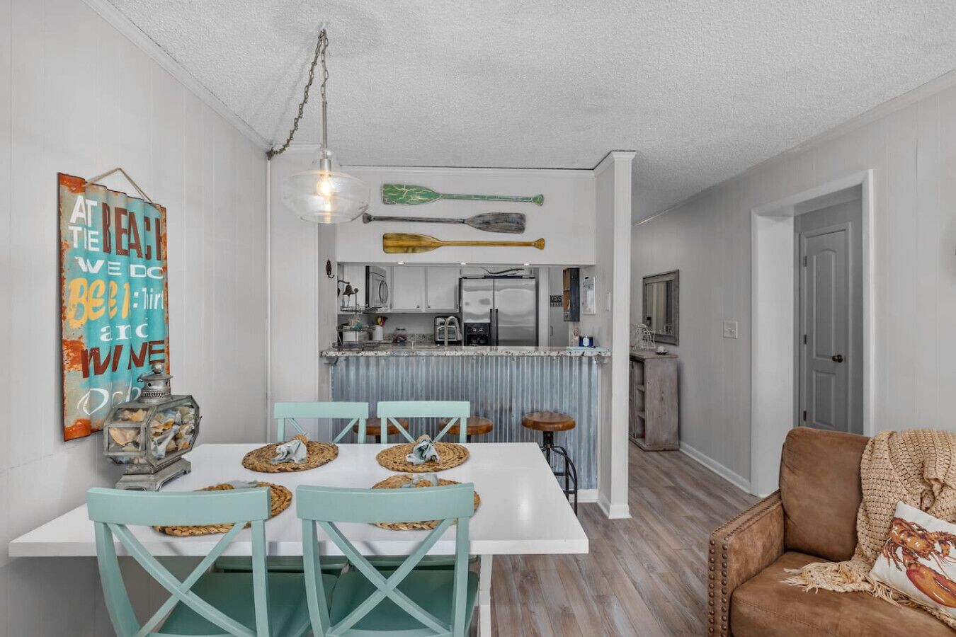 A compact kitchen with a white countertop, a hanging green paddle, and a rustic sign on the wall.