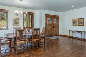 A dining area with a wooden table and chairs, a chandelier, and a large wooden door. - Grand Estate Close to Ski Resort with Hot Tub (Durango)
