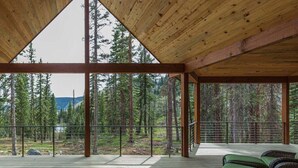 Une vaste terrasse en bois offrant une vue sur une forêt et des montagnes.