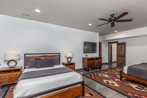A hotel room with a large bed, a ceiling fan, a TV, and a wooden dresser. - Grand Estate Close to Ski Resort with Hot Tub (Durango)