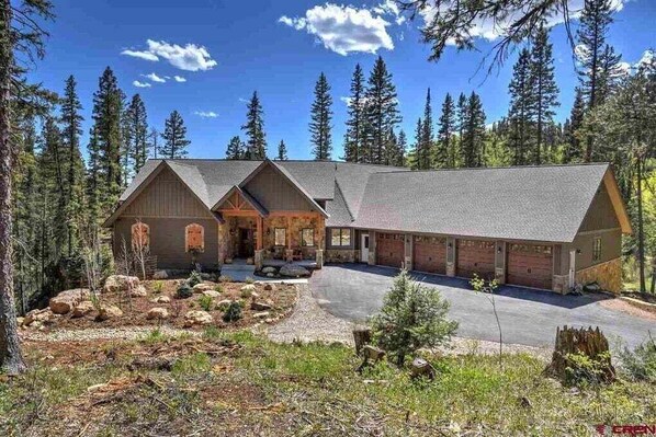 A large, two-story log cabin with a garage, surrounded by a forest. - Grand Estate Close to Ski Resort with Hot Tub (Durango)