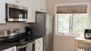Eine moderne Küche mit Edelstahlgeräten, einer Kaffeemaschine und einem Fenster mit Blick auf Bäume.