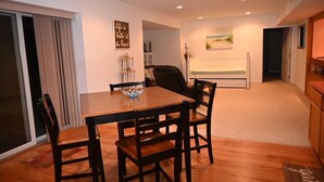 Un coin repas avec une table et des chaises en bois, une porte-fenêtre coulissante et un tableau au mur.