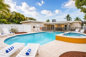 A swimming pool with lounge chairs and a covered patio area.