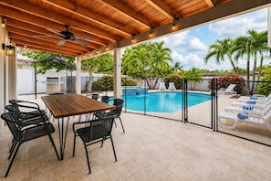 An outdoor patio with a wooden table and chairs, a pool, and lounge chairs. - Premium Luxury  5BR/4BA Villa near Hollywood Beach (Hollywood)