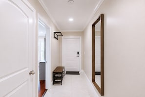 A hallway with white doors, a bench, and a mirror on the wall.