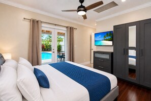A bedroom with a bed, a TV, a wardrobe, and a view of a pool.