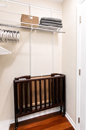 A storage closet with shelves, a wicker basket, folded towels, and a wooden crib. - Premium Luxury  5BR/4BA Villa near Hollywood Beach (Hollywood)