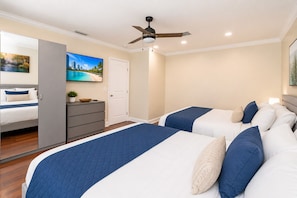 A bedroom with two beds, a wardrobe, a TV, and a ceiling fan.