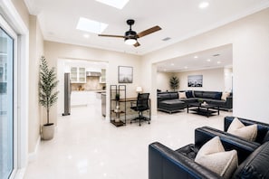 A modern living room with a sofa, coffee table, and a dining area with a chair and table.
